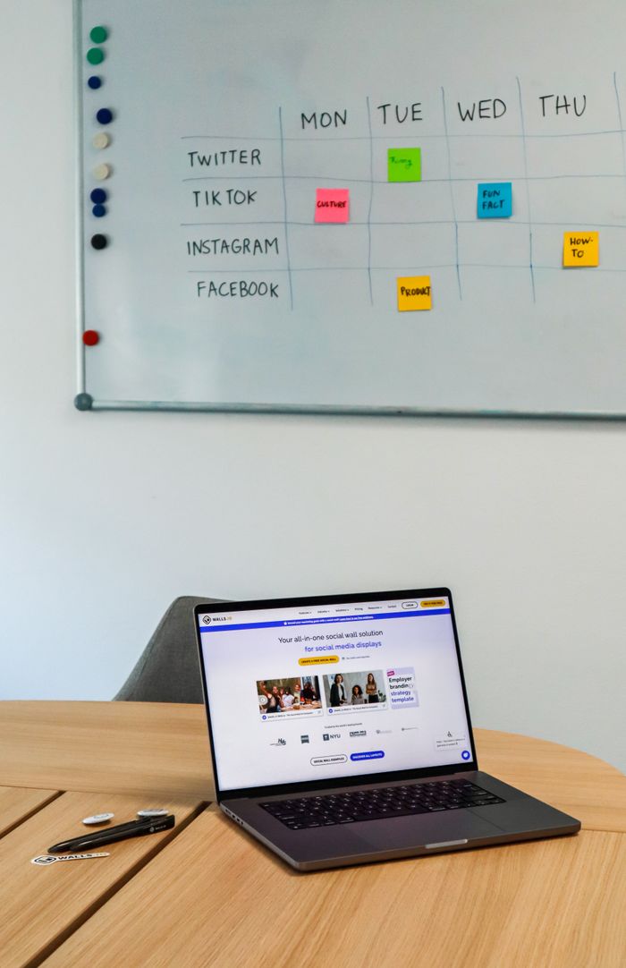about-04 Un aménagement de bureau moderne avec un ordinateur portable et un planning sur tableau blanc pour les plateformes de réseaux sociaux.